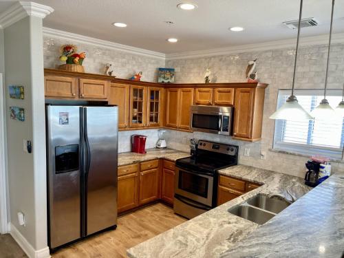 a kitchen with wooden cabinets and a stainless steel refrigerator at Beachgate Condo Suites and Hotel 341 condo in Port Aransas