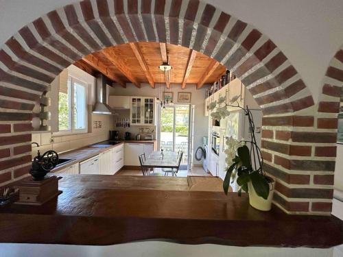 une grande cuisine avec une arche en pierre avec une table dans l'établissement Chalet de Cornalis, à Morcenx