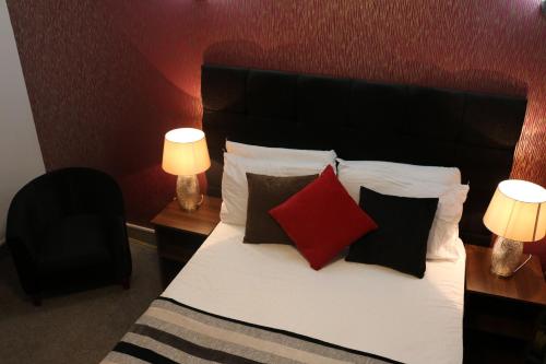 a bedroom with a bed with red and black pillows at Trivelles Mayfair,stockport in Manchester