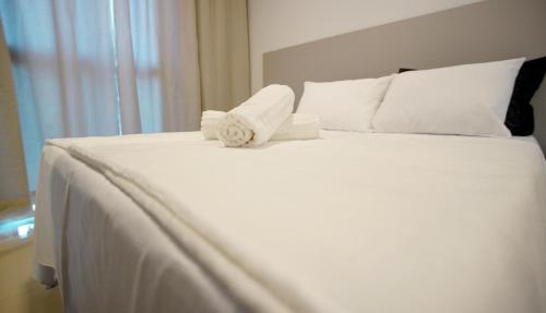 a white bed with two rolled towels on it at Studio completo no Daia-Anápolis em frente a Caoa in Anápolis