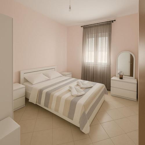 a white bedroom with a bed and a mirror at Harmony family house in Skála Nikíta