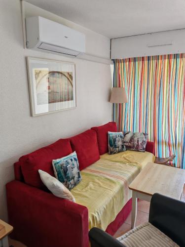 un salon avec un canapé rouge et une table dans l'établissement Le Cap d'Agde 2 pièces climatisé résidence Odalys St Loup en RDC avec terrasse, au Cap d'Agde