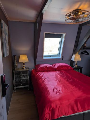 a bedroom with a red bed and a window at WitteZwaan in Harlingen