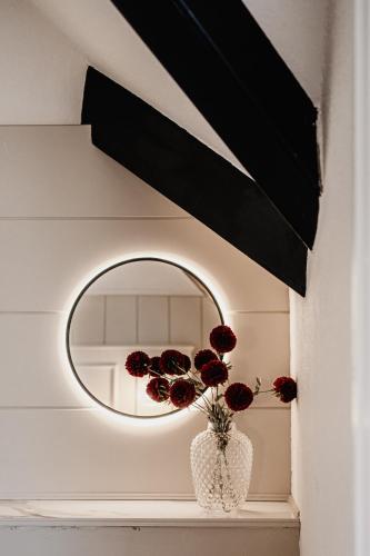 a round mirror with red flowers in a vase on a shelf at The Yorkshire Unicorn in Skipton