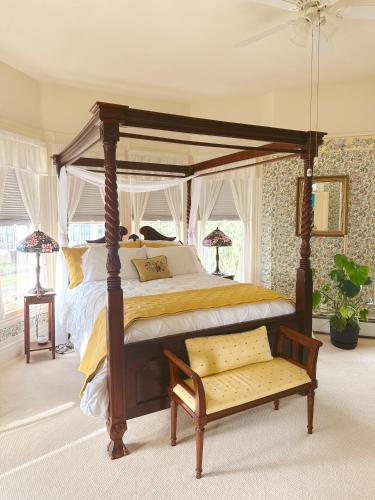 a bedroom with a canopy bed and a bench at Adams Pragge House - Victorian Bed & Breakfast in Port Townsend