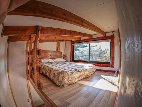 a bedroom with a bed and a large window at Cabañas Sendero del Zorro in Chillán