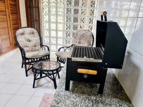 Una estufa negra con dos sillas y una mesa. en Casa encantadora 900m da PRAIA de Itaipuaçu, en Maricá