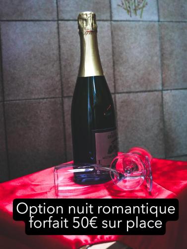 a bottle of wine sitting on a red table at Le Ptit Abri in Les Avenières