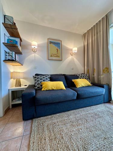 un canapé bleu avec des coussins jaunes dans un salon dans l'établissement Appartement climatisé avec piscine et jardin à l'entrée du Golfe de St Tropez, à La Garonnette-Plage