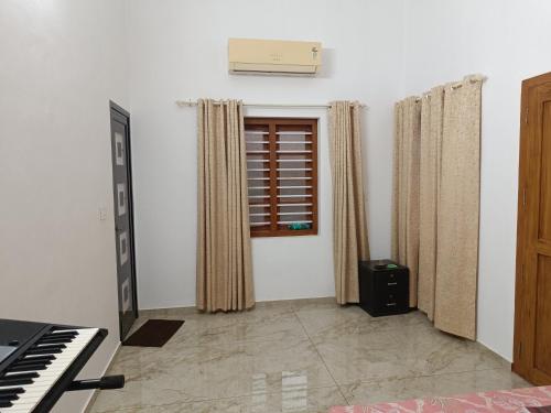 a living room with a piano and a window at La casona in Kottayam