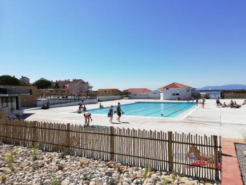 un groupe de personnes se promenant autour d'une piscine dans l'établissement Beau appartement face à l eau, au Barcarès