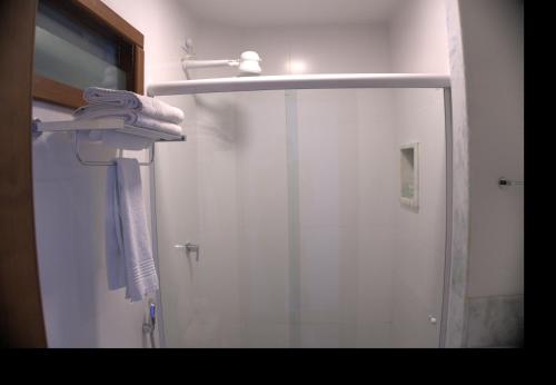 a shower with a glass door and a towel at Pousada da Ladeira in Pipa