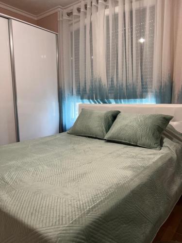 a bed with two pillows in front of a window at Durres Relax Holiday Home in Qerret