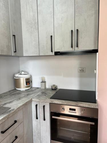 a kitchen with white cabinets and a stove top oven at Durres Relax Holiday Home in Qerret