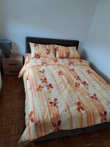 a bed with a comforter with flowers on it at Apartman MAGNIFICO in Donje Mladice