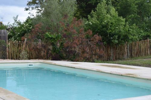 a blue swimming pool in front of a wooden fence at Zélie Gîte in Ambillou-Château