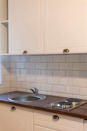 a kitchen counter with a sink and white cabinets at #Comfy Apartment in Old Town in Timişoara