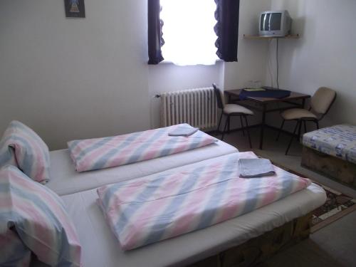 two beds in a room with a table and chairs at Penzión Slávia in Poprad