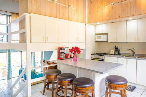 a kitchen with white cabinets and a counter with stools at Loft Apartment Ocean View in Saint Johnʼs