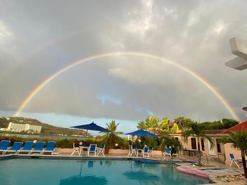 a rainbow over a pool with chairs and a pool at Loft Apartment Ocean View in Saint Johnʼs