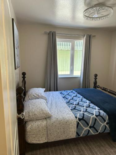 a bedroom with a bed with a blue comforter and a window at Comfort and Cozy in Fairbanks !! in Fairbanks