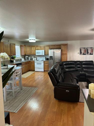 a living room with a black leather couch and a kitchen at Comfort and Cozy in Fairbanks !! in Fairbanks