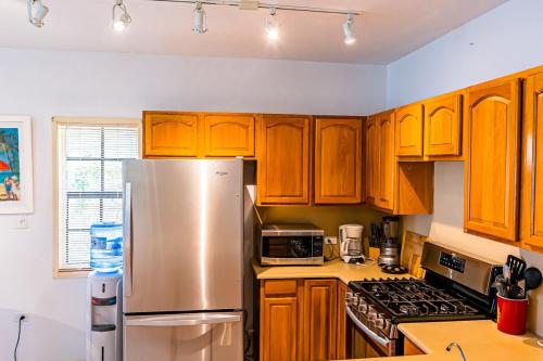 a kitchen with wooden cabinets and a stainless steel refrigerator at Perfect Hillside Ocean View in Saint Johnʼs