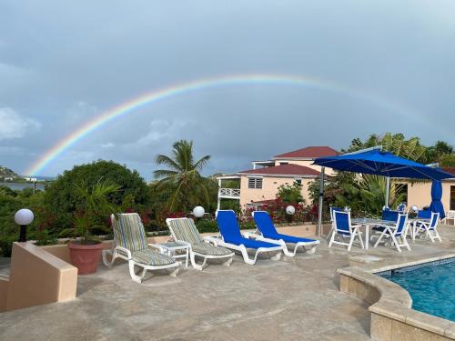 a rainbow over a patio with chairs and a pool at Perfect Hillside Ocean View in Saint Johnʼs