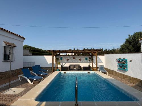 a swimming pool with chairs and a pergola at casa lucia in Cádiz