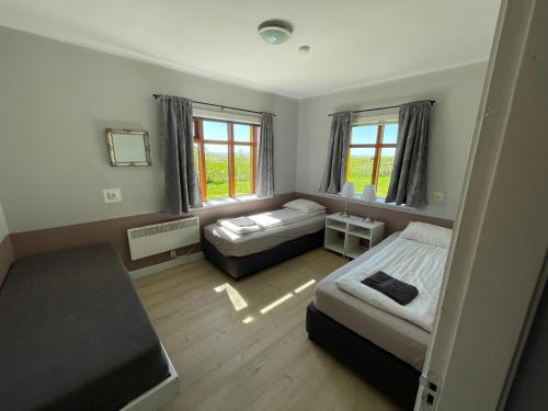 a bedroom with two beds and two windows at Lækjarhus Farm Holidays in Borgarhöfn