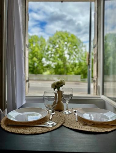 une table avec deux assiettes et des verres et une fenêtre dans l'établissement Studio 0 - Cinema Sports Parking - DABNB, à Limoges