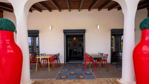a patio with tables and chairs and red vases at Casa Nova Maison d'hôtes in Sagone
