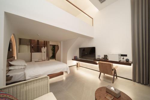a white bedroom with a bed and a table at Zhangjiajie Tianmenshan Xuyuan Hotel in Zhangjiajie