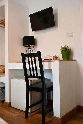 a black chair sitting at a desk with a tv on the wall at Matinee Rooms in Mattinata