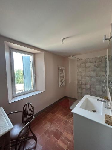 a bathroom with a sink and a chair and a window at Gîte de Montplo-Cruzy in Cruzy