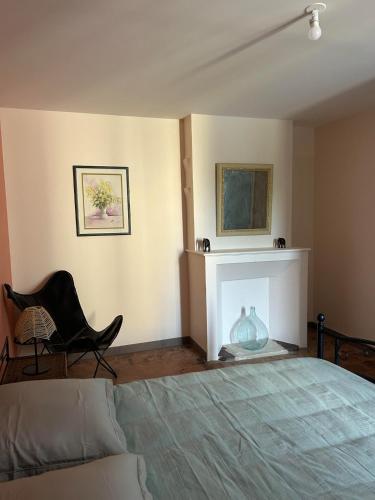 a bedroom with a bed and a chair and a fireplace at Gîte de Montplo-Cruzy in Cruzy