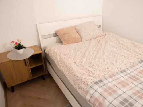 a bedroom with a bed and a nightstand with a table at Apartament Vikicentrum in Bolesławiec