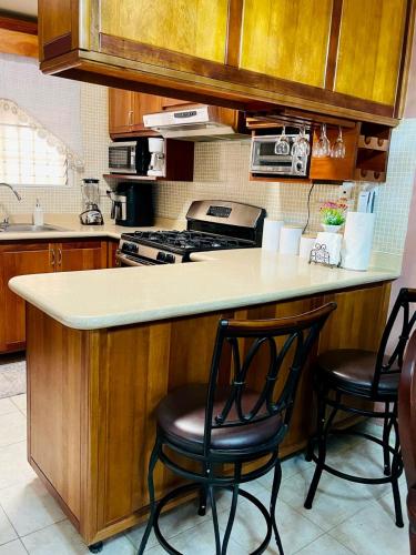 a kitchen with a counter with two chairs and a stove at FreshBreeze - Apartment Near US Embassy in Santo Domingo