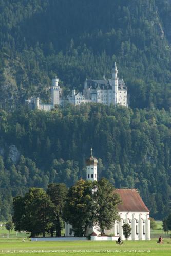 a castle on top of a hill with a house at Ziegelberg Chalets in Füssen