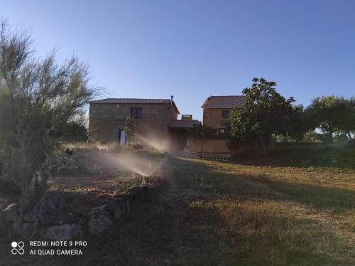a house with a sprinkler in front of a yard at Quinta Damigo in Seia