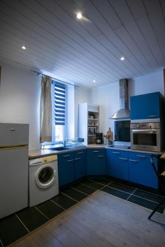 une cuisine avec des armoires bleues et une machine à laver dans l'établissement Duplex cosy-Wifi-Parking-Netflix-Lyon 9, à Lyon