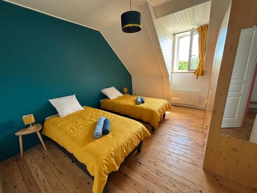 deux lits dans une chambre avec des draps jaunes dans l'établissement Bel appartement avec jardin à la campagne, à Plomodiern