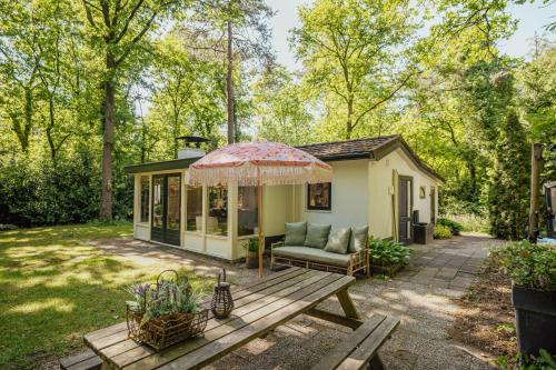 a tiny house with a picnic table and an umbrella at Boshuisje op de Veluwe in Nunspeet