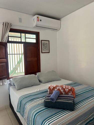 a bedroom with a bed with a blanket and a window at Casa Mangue in Soure