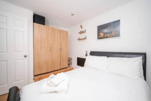 a bedroom with a white bed and a wooden cabinet at Cosy ,Private Accommodation in Lower Sydenham Station