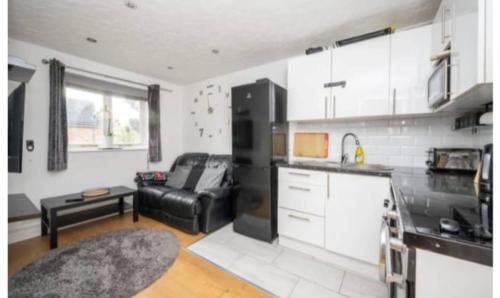 a kitchen with a black refrigerator and a couch at Cosy ,Private Accommodation in Lower Sydenham Station