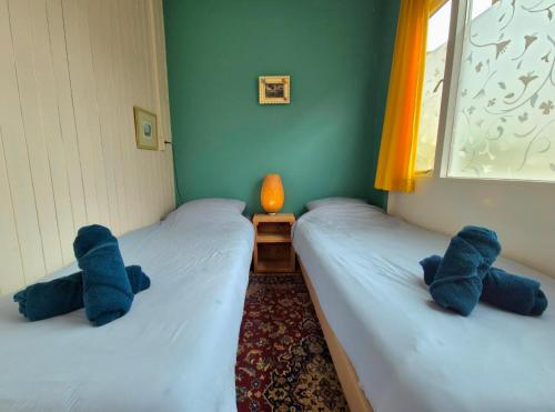 zwei Betten in einem Zimmer mit blauen Stofftieren darauf in der Unterkunft Bungalow Texel near beach and city centre in De Koog