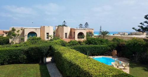 ein großes Haus mit einem Swimmingpool im Hof in der Unterkunft 3-Bedroom Furnished Apartment - Golden Beach Resort, North Coast in Dawwār Ibrāhīm Abū Shunaywīr