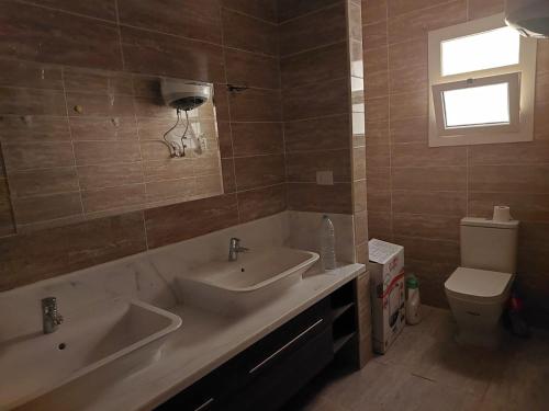 ein Badezimmer mit zwei Waschbecken und einer Toilette in der Unterkunft 3-Bedroom Furnished Apartment - Golden Beach Resort, North Coast in Dawwār Ibrāhīm Abū Shunaywīr