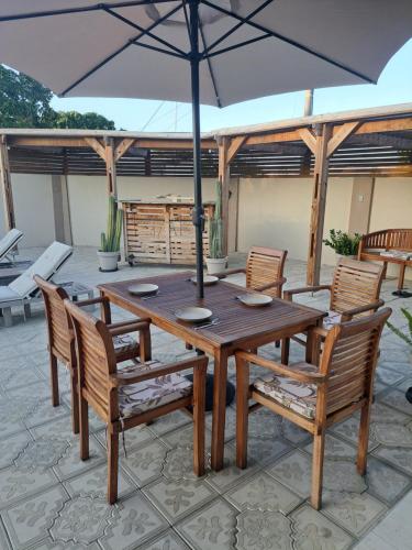 a wooden table and chairs with an umbrella on a patio at Lovely Caribbean family villa with private pool in Willemstad